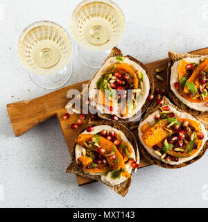 Gustosa bruschettes con hummus, cotta di zucca e pesto di rucola sul tavolo. vegan cibo sano e servita con vino bianco Foto Stock