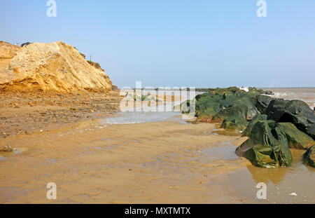 Una vista della spiaggia tra rock corazza mare difese e erodendo scogliere sulla costa di Norfolk a Happisburgh, Norfolk, Inghilterra, Regno Unito, Europa. Foto Stock