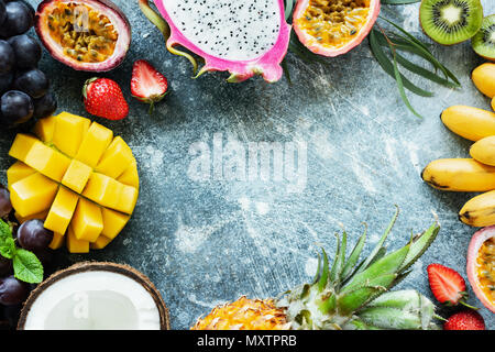 Telaio di fresca frutta tropicale su calcestruzzo sfondo con copia spazio per testo, vista dall'alto. Concetto di estate, frutti esotici, vegane e paleo dieta Foto Stock