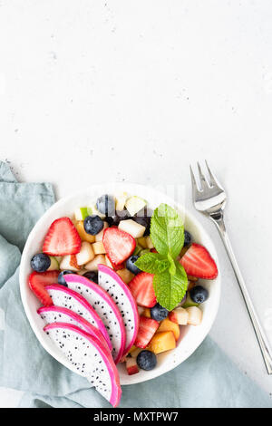 Esotica frutta tropicale con insalata di frutta drago in bianco ciotola, vista dall'alto. Frutta tailandese insalatiera. Vegetariano, paleo dieta, mangiare sano e in estate concep Foto Stock