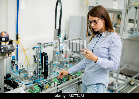 Piuttosto giovane donna con tavoletta digitale nel laboratorio di elettronica Foto Stock