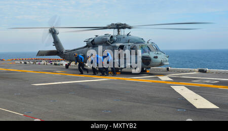 I marinai assicurano un elicottero MH-60S Knighthawk sul ponte di volo della nave d'assalto anfibia USS Iwo Jima (LHD 7) durante le operazioni di volo nell'Oceano Atlantico, 5 dicembre 2016. La nave sta conducendo certificazioni pre-implementazione per Mobility-Engineering e Mobility-Seaman. L'MH-60S è un elicottero multiruolo utilizzato per combattimento in mare, ricerca e salvataggio e logistica. Le operazioni in cabina di pilotaggio garantiscono la prontezza operativa, le procedure di sicurezza e il coordinamento tra l’equipaggio di condotta e il personale di coperta. Foto Stock