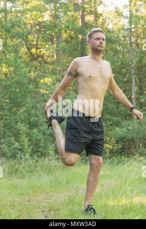 Barechested metà adulto 40s uomo caucasico facendo si allunga la gamba prima di esercizio Foto Stock