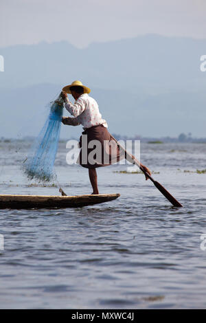 Un pescatore locale per dimostrare il carattere distintivo della gamba tecnica di canottaggio sul Lago Inle, Birmania. Foto Stock