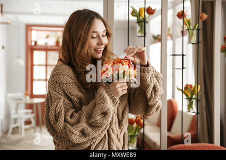 Foto di bella donna in maglia maglione azienda fiore straordinario nel ristorante o bar Foto Stock