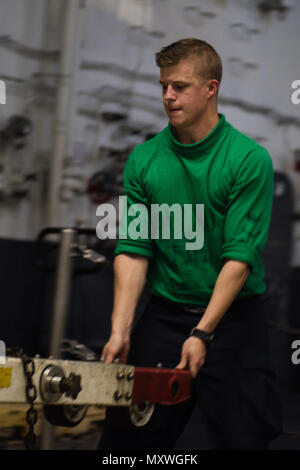 161210-N-ZO915-006 OCEANO PACIFICO (dec. n. 10, 2016) Petty Officer di terza classe Alex Scott, da Panama City, Florida, pile di aeromobili di barre di traino in USS John C. Stennis' (CVN 74) hangar bay. John C. Stennis è in corso per condurre la formazione di routine nella terza area della flotta di responsabilità. (U.S. Navy foto di Sottufficiali di seconda classe Jackson G. BROWN / rilasciato) Foto Stock