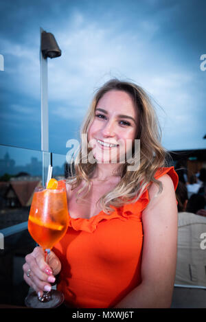 La moda e lo stile di vita di blogger Andreea Rasclescu presso il bar sul tetto in Oxford, The Varsity Club, bevendo un bicchiere di colore arancione di Aperol per abbinare il suo Outfit Foto Stock