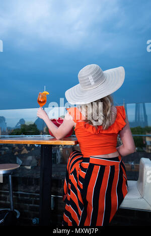 La moda e lo stile di vita di blogger Andreea Rasclescu presso il bar sul tetto in Oxford, The Varsity Club, bevendo un bicchiere di colore arancione di Aperol per abbinare il suo Outfit Foto Stock