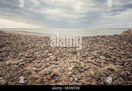 Selvaggia spiaggia di pietra sulla costa del mar mediterraneo con cielo nuvoloso e orizzonte di Sanlucar de Barrameda Foto Stock