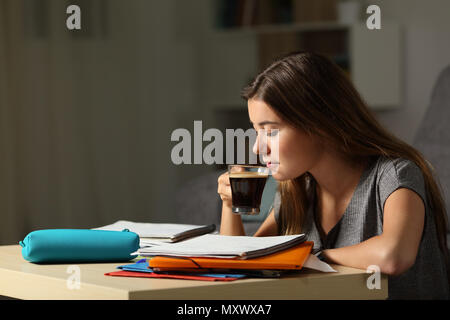 Vista laterale verticale di una studiosa studente di bere caffè late hous nella notte a casa Foto Stock