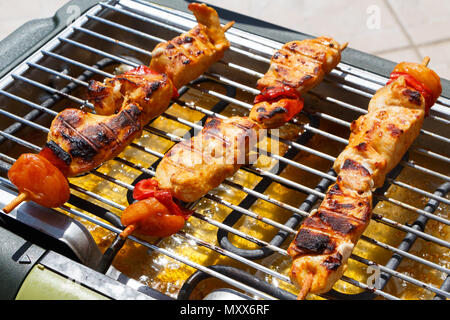 Pollo Marinato con spiedino di pepe e albicocca secca sulla griglia di un barbecue elettrico Foto Stock