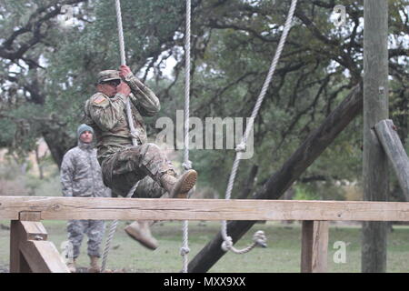 Pvt. 2 Michael A. tedesco, assegnati i militari gli onori funebri plotone, sede centrale della Società di assistenza, sede del Quartier Generale battaglione, U.S. Esercito Nord (Quinto esercito) oscilla su un ostacolo sulla fiducia corso durante la annuale Guardian sfida a Camp Bullis il 9 dicembre. Dodici squadre di due persone mettere le loro competenze al test come si sono mossi per ogni evento a piedi portando un 30-pound zaino. Le squadre hanno gareggiato in un esercito modificati Physical Fitness Test, corso di fiducia, armi gamma di qualificazione - cottura sia M9 pistola e M16 fucile, e due attività medica. Foto Stock