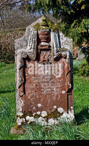 Lapide in pietra arenaria con urna drappeggiato, libro e di agnello e bandiera design. Chiesa di San Bartolomeo, Loweswater, Parco Nazionale del Distretto dei Laghi, Cumbria. Foto Stock