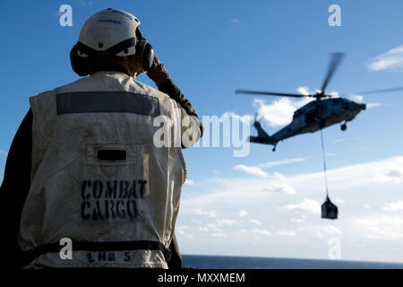 Un elicottero MH-60S Seahawk della Marina degli Stati Uniti trasferisce il carico alla nave d'assalto anfibia USS Bataan (LHD 5) mentre è in corso nell'Oceano Atlantico il 9 dicembre 2016. L'MH-60S è un elicottero bimotore, multi-missione, alimentato da due motori turboalbero General Electric T700 e gestito da squadroni Helicopter Sea Combat. La USS Bataan stava partecipando ad un'esercitazione Amphibious Ready Group e Marine Expeditionary Unit. Foto Stock
