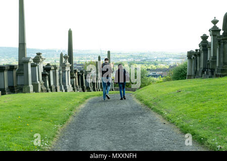Uomo e donna vanno attraverso la necropoli di Glasgow, Scozia Foto Stock