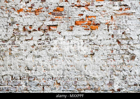 Vecchio e stagionato grungy rosso mattone parete parzialmente dipinto di bianco con pareti scrostate e coperte da vecchio cemento come sfondo di texture. Foto Stock