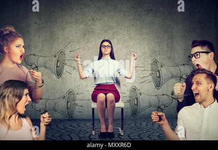 Meditando impassibile giovane imprenditrice presta alcuna attenzione alla folla di urlando nel megafono arrabbiato persone Foto Stock