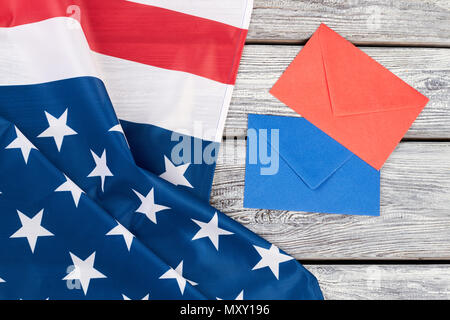 Bandiera degli Stati Uniti e le buste colorate. Bandiera nazionale d'America, blu e busta rossa su sfondo di legno, vista dall'alto. Foto Stock