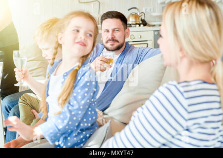 Ritratto di famiglia felice con due bambini seduti sul divano gustando una cena festosa parte a casa, focus sulla cute dai capelli rossi ragazza volgendo lo sguardo al suo mo Foto Stock