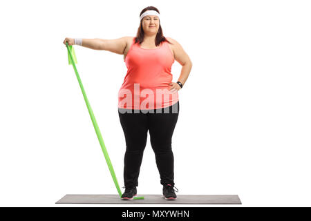 A piena lunghezza Ritratto di una donna sovrappeso esercizio con un nastro di gomma su un tappeto isolato su sfondo bianco Foto Stock