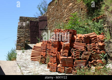 Pila di argilla tegole del tetto. Il materiale di costruzione per edilizia. Vista laterale di una pila di rosso marrone tegole del tetto nella parte anteriore del borgo medievale di muro di pietra. Clay Foto Stock