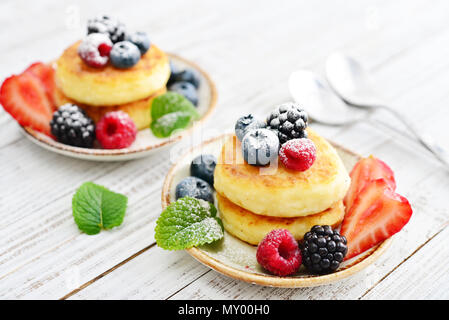 Cottage cheese pancakes, syrniki, frittelle di cagliata con frutti di bosco freschi su sfondo di legno Foto Stock