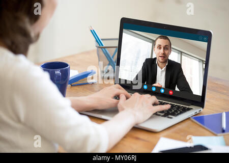 Imprenditrice rendendo la chiamata video al business partner utilizzando laptop. Close-up vista posteriore della giovane donna avente la discussione con il cliente aziendale. Jo remoto Foto Stock