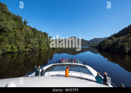 Crociera in barca sul fiume Gordon con turisti in cerca in corrispondenza dello specchio simili riflessioni, costa Ovest della Tasmania Foto Stock