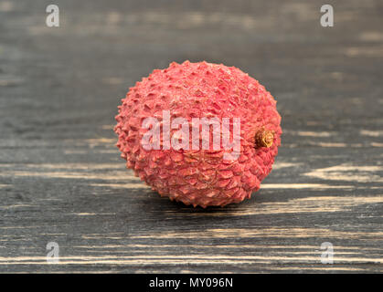 Il lychee cinese frutta in guscio su sfondo di legno Foto Stock