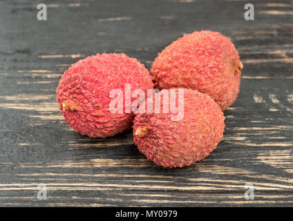 Tre cinesi frutta lychee closeup al buio su un tavolo Foto Stock