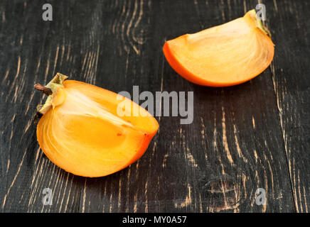 Due deliziose fette di frutta persimmon sul tavolo scuro Foto Stock