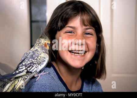 Giovane ragazza sorride a pet bird seduto sulla sua spalla. Il sig. © Myrleen Pearson Foto Stock