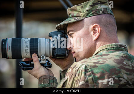 Sgt. Brandon Hubbard, un affari pubblici sottufficiale con il 204th Affari pubblici distacco, 99th regionale di sostegno e di comando scatta foto durante un trasferimento di autorità cerimonia dic. 19, 2016 a Camp Arifjan in Kuwait. Hubbard è un U.S. La riserva di esercito soldato schierato in Kuwait per fornire foto professionali e stampa supporto giornalistico di U.S. Esercito centrale. (U.S. Esercito foto di Sgt. Angela Lorden) Foto Stock