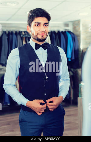 Ragazzo sta cercando sull'immagine scelta di fronte allo specchio in uomini shop. Foto Stock