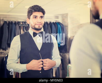 Maschio è il tentativo sull'immagine scelta di fronte allo specchio in uomini shop. Foto Stock