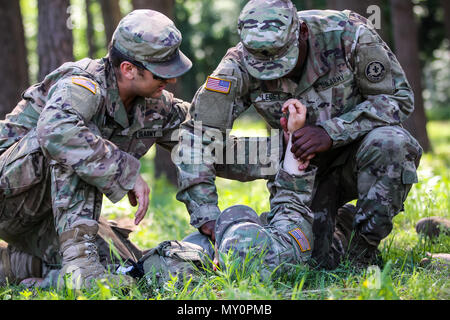 Spc. Steve Scheel (sinistra), Mukilteo, nativo di Washington, combattere medic con il primo squadrone, 2° reggimento di cavalleria,insegna Spc. Dario Ledet (a destra), Lafayette, Louisiana nativo, fuoco indiretto fantassin con il primo squadrone, 2° reggimento di cavalleria, come controllare un soldato di impulso dei durante il combattimento ancora di salvezza la formazione con gruppo di combattimento della Polonia a Bemowo Piskie Area Formazione, Polonia, 31 maggio 2018. Gruppo di combattimento della Polonia è un luogo unico e multinazionale di coalizione di Stati Uniti, Regno Unito, croato e soldati rumeni che servono con il polacco della XV Brigata meccanizzata come una forza di dissuasione in sostegno della NATO è stato ottimizzato in avanti delle prese Foto Stock