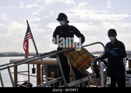 Coast Guard trasferita la custodia dei due sospetti di contrabbandieri e più balle di cocaina alla legge federale alle autorità incaricate di far rispettare la legge a Coast Guard Settore San Juan a San Juan, Puerto Rico nov. 10, 2016. In totale, 1.158 libbre di cocaina con una stima di valore all'ingrosso di $13.1 milioni di euro sono stati sequestrati come risultato multi-agenzia legge gli sforzi a sostegno dell'operazione Unified risolvere e funzionamento dei Caraibi di protezione. (U.S. Coast Guard foto di Ricardo Castrodad) Foto Stock