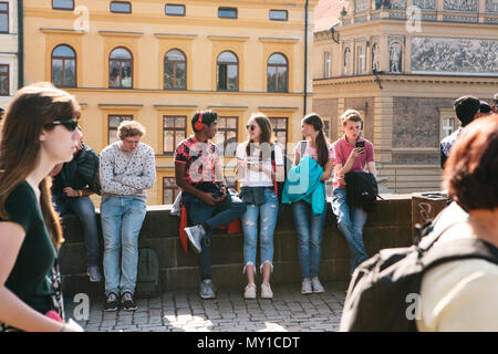 Repubblica Ceca, Praga - 29. 09. 2017. Gruppo di diversi giovani raffreddamento sul lungofiume di ciottoli nella giornata di sole Foto Stock