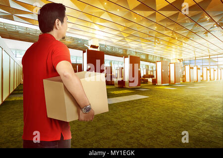 Attraente consegna asiatici uomo portare il pacchetto a consegnare su edificio moderno Foto Stock
