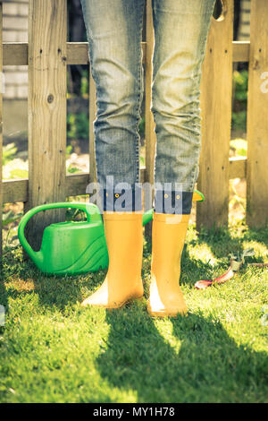 Giardiniere indossando giallo wellies stivali in giardino, tonica immagine Foto Stock