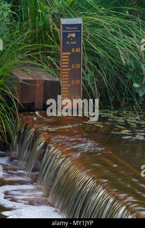 Gestione delle risorse idriche: un piccolo weir e di un misuratore di livello in un fiume olandese Foto Stock