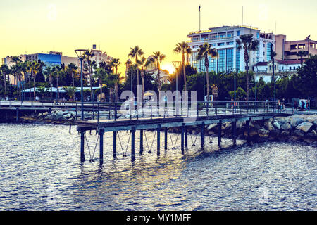 Vista al tramonto per città e acqua. La gente che camminava sul lungomare vicolo e rilassante in ristoranti. Copia negativo spazio, posto per testo, Limassol, Cipro Foto Stock