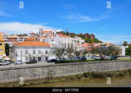 Vista della città con il castello e la Cattedrale per la parte posteriore e alberi di jacaranda in fiore in primo piano, Silves, del Portogallo, dell'Europa. Foto Stock