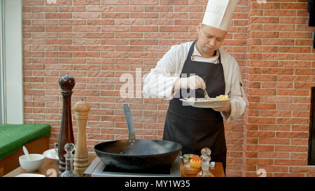 Professionale chef cucinare pesce in padella Foto Stock
