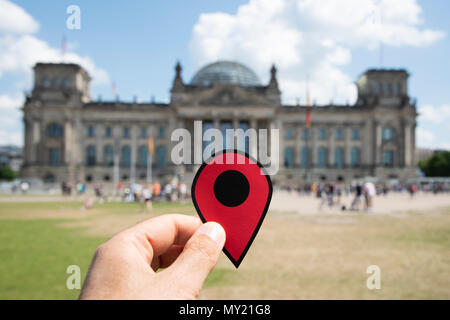 Primo piano della mano di un giovane uomo caucasico con un indicatore rosso nella parte anteriore dell'Edificio del Reichstag a Berlino, Germania Foto Stock