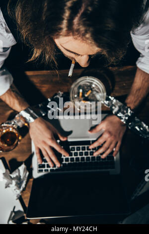 Giovane uomo utilizzando laptop e Sigaretta fumare Foto stock - Alamy