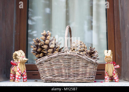 Cestino con pigne nella finestra stagione invernale dai toni morbidi sfondo, Anno Nuovo e le decorazioni di Natale in cesto tessuto con pigne backgroun Foto Stock