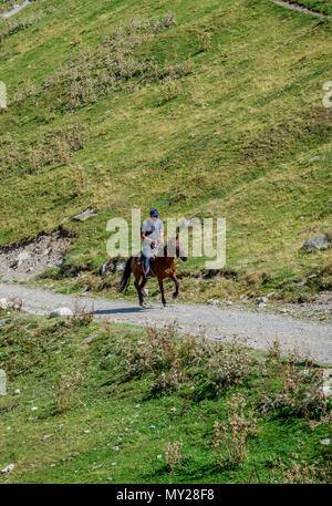 Ushguli, Georgia - 6 Settembre 2017: l'uomo al galoppo con cavallo sulla strada nel villaggio di Ushguli, Svaneti Foto Stock