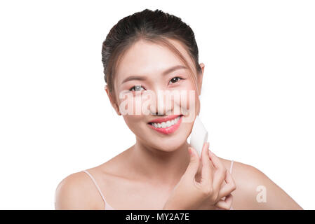 Donna attraente mettendo sul make up, liquido applicato foundation sul suo viso Foto Stock