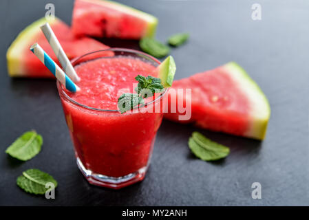 Bicchiere di anguria frullato fresco con fette di anguria nero su sfondo di ardesia Foto Stock